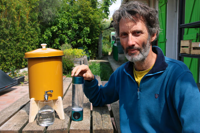 Ecofiltro filtre à gravité argile dans une cuisine moderne, verre d'eau filtrée, design artisanal